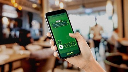 a person's hand holding a cell phone displaying a UO themed word game